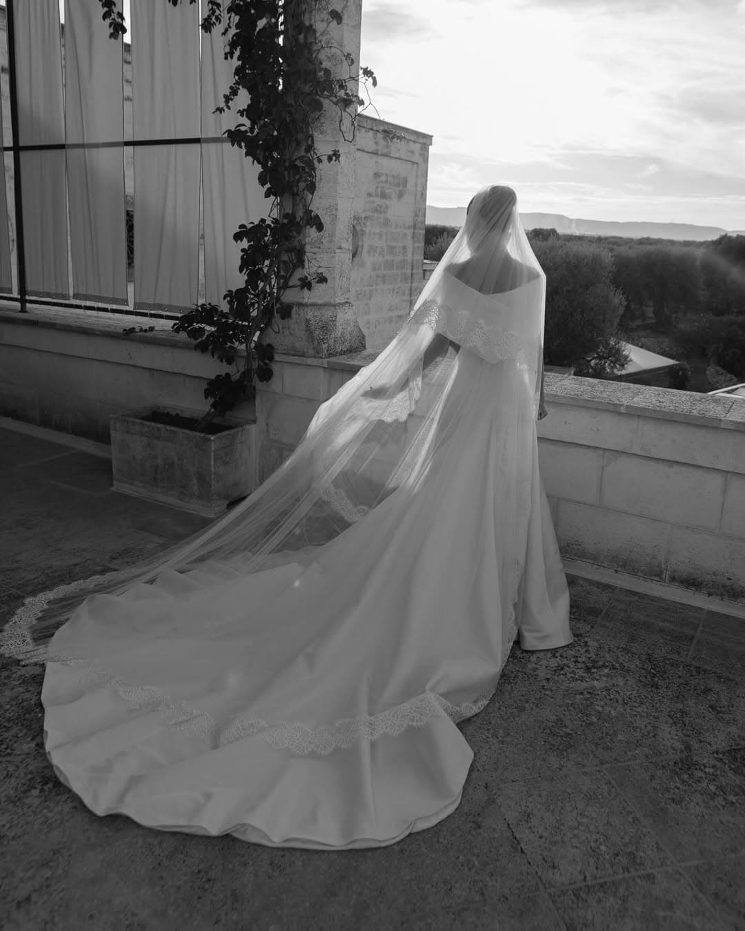 Mariée de dos au coucher du soleil, longue traîne et voile brodé