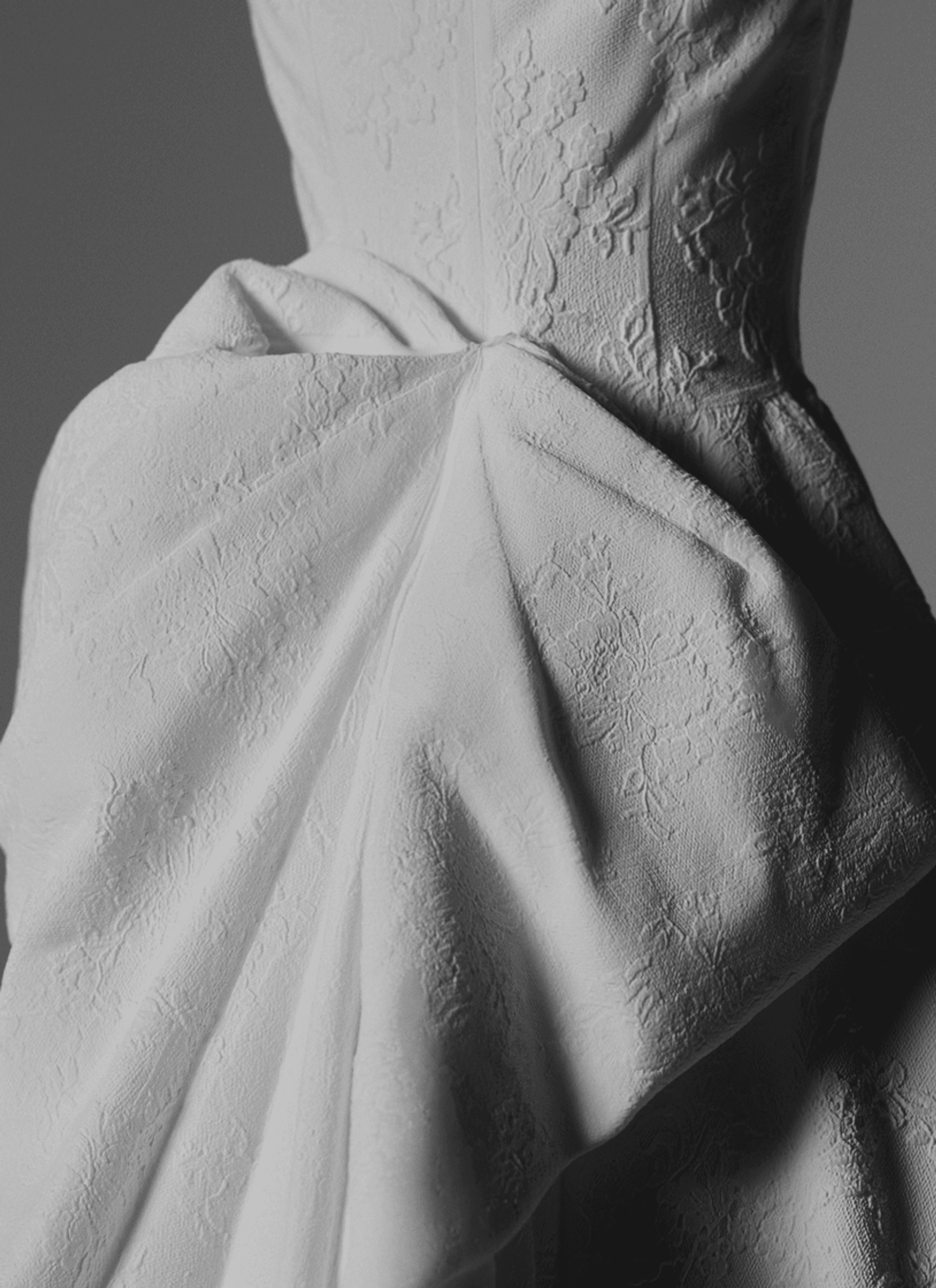 Dos d'une robe de mariée en couture sur fond ambré